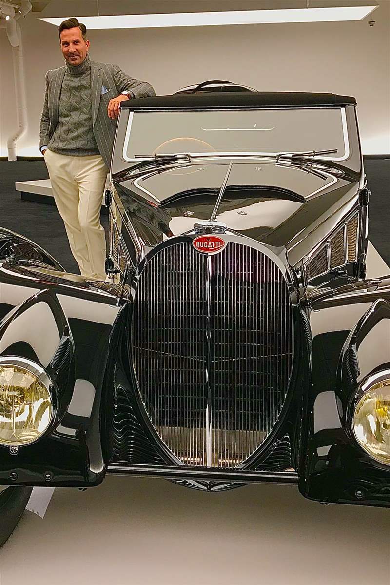 一個男人在一輛老爺車旁邊擺姿勢